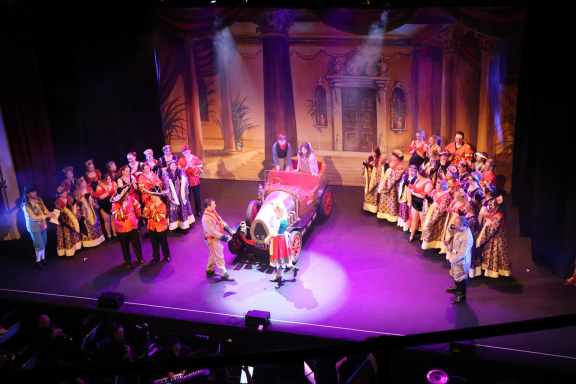 A vibrant stage performance with performers in elaborate costumes and theatrical lighting.
