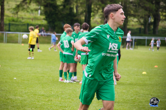 Young football players in green kits training on a grassy field.