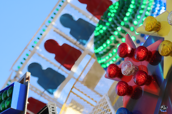 Colourful amusement park attraction with bright decorations and silhouettes of people.