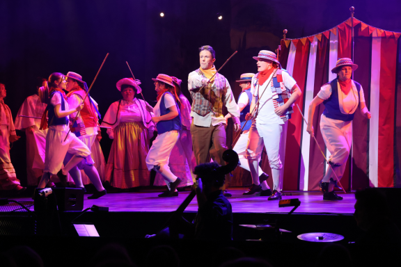 A lively theatre performance featuring dancers and musicians on stage.