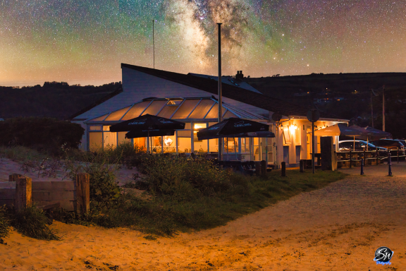 A seaside building illuminated at night under a starry sky.