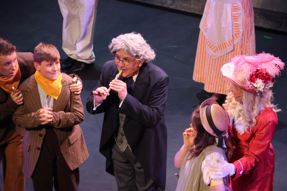 A theatrical scene with performers in period costumes engaging in a lively performance.