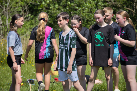 A group of children outdoors, engaged in conversation during a sunny day.