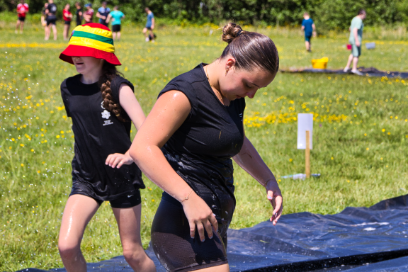 Children playing in a water activity on a sunny day, wearing swimwear and having fun.