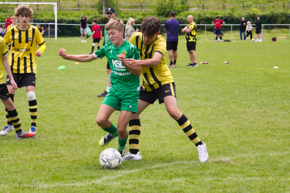 Two young football players compete for the ball on a grassy field.