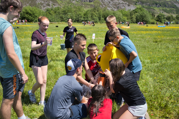 A group of children and teenagers playing together in a grassy field.
